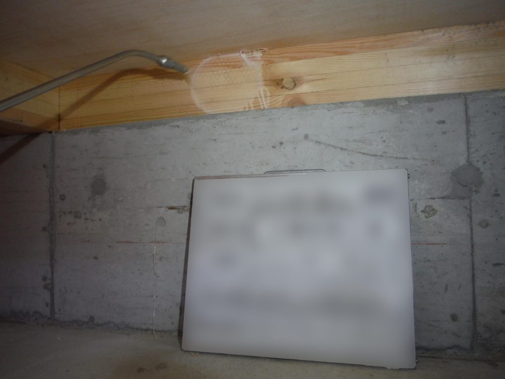 シロアリ木部処理の写真。床下の木材部分にシロアリ予防薬を吹き付ける様子。